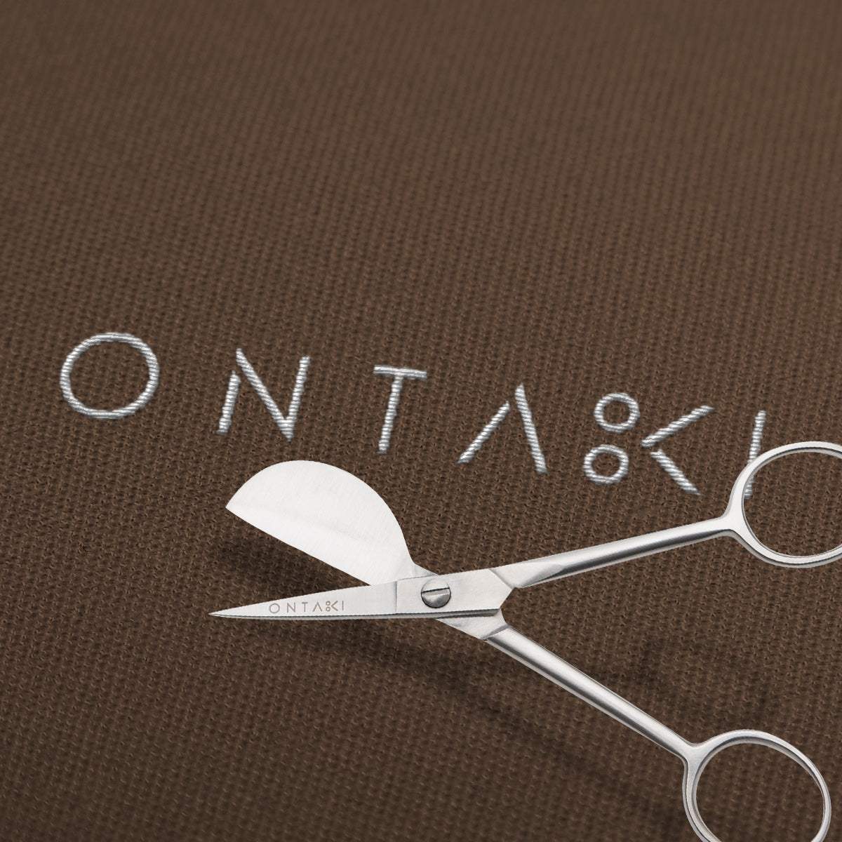Silver scissors with 'ONTAKI' branding on a brown background